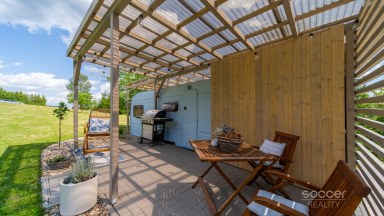 Příjemná venkovská zahrada s rekreačním karavanem a terasou.