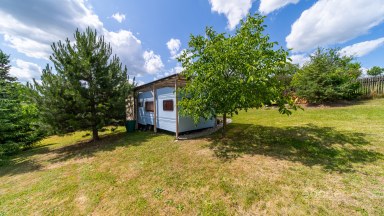 Příjemná venkovská zahrada s rekreačním karavanem a terasou.
